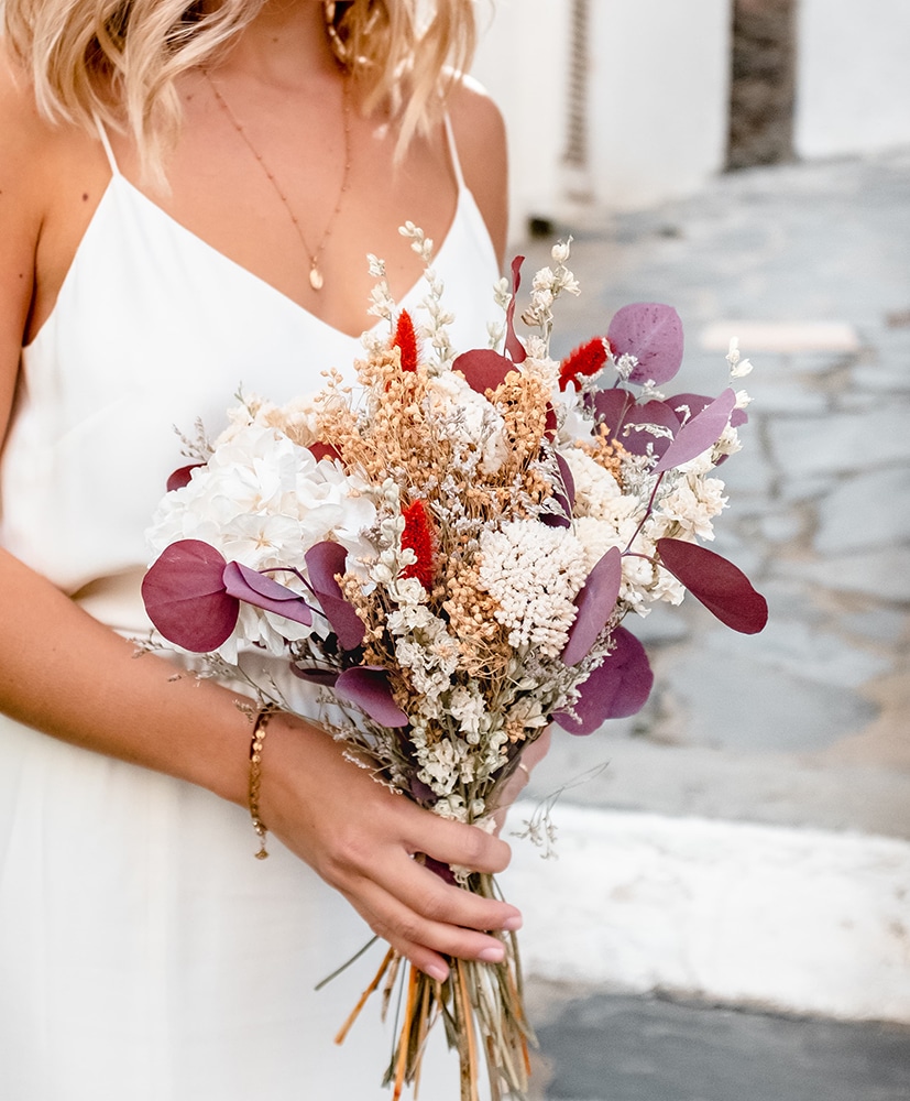 Bouquet de mariée en fleurs séchées dans les ton orangés dans les bras de la mariée