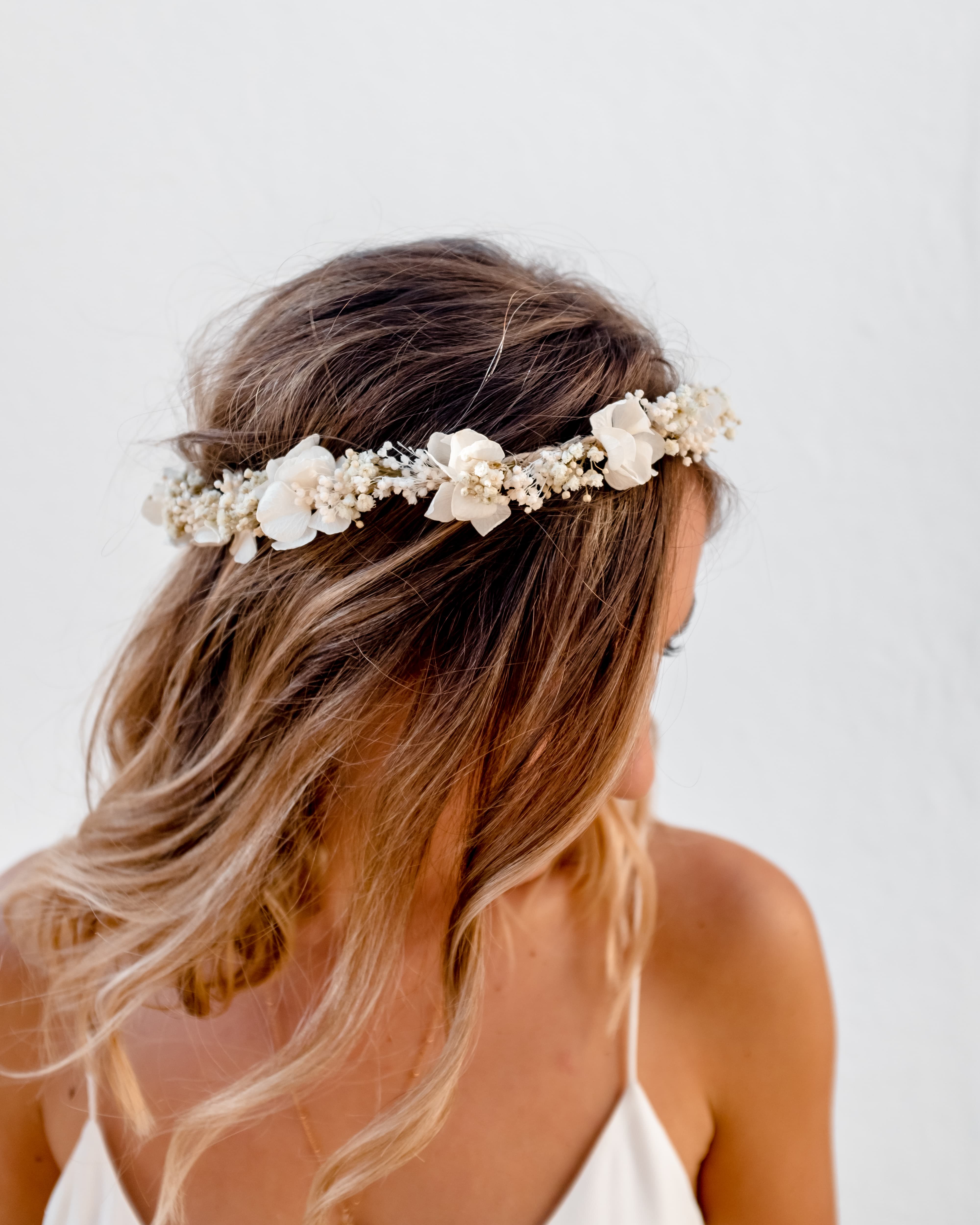 Femme blonde qui porte une couronne de fleurs séchées blanches de chez rosa cadaqués