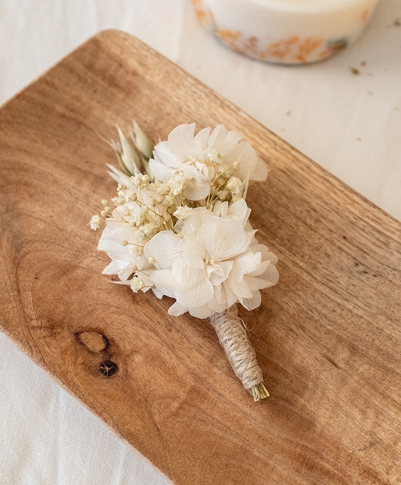 Boutonnière de fleurs séchées blanches Rosa Cadaqués posé sur une planche en bois
