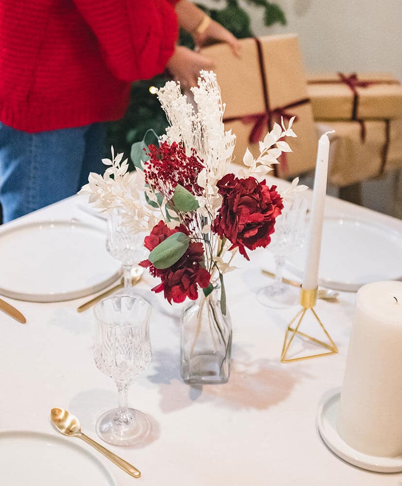 composition d'hortensia rouge et de feuillage blanc dans un soliflore posé sur la table